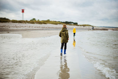 Rear view full length of boy running with sister at beach