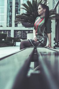 Thoughtful woman sitting on bench by potted plant