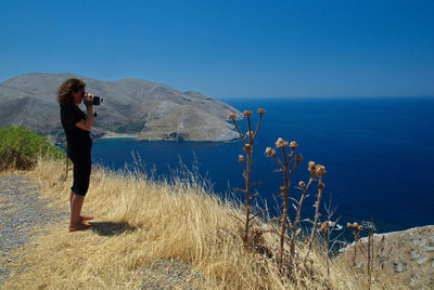 Woman standing by sea against clear blue sky