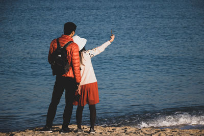 Rear view of man and woman standing at sea shore