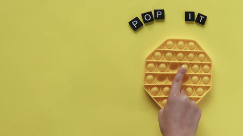 Close-up of human hand against yellow background