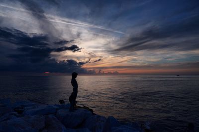 Man looking at sea against sky during sunset