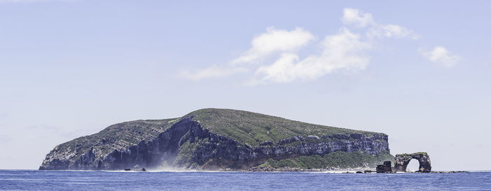 Sea by mountain against sky