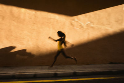 Side view of woman running on wall