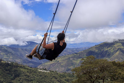 Woman paragliding over mountain against sky