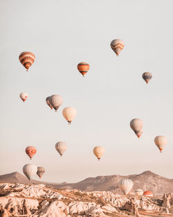 Hot air balloons flying over landscape against sky