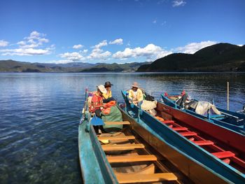 People on boat in lake against sky