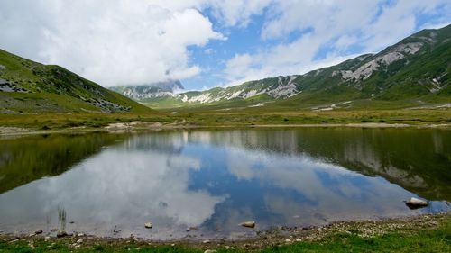 Scenic view of lake by mountains against sky
