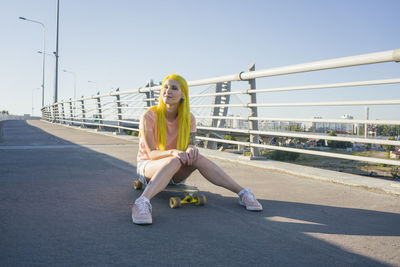 Full length of man sitting on bridge against sky