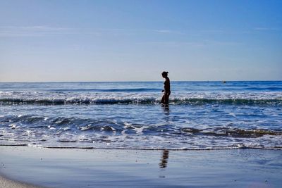 Silhouette man standing on beach against sky