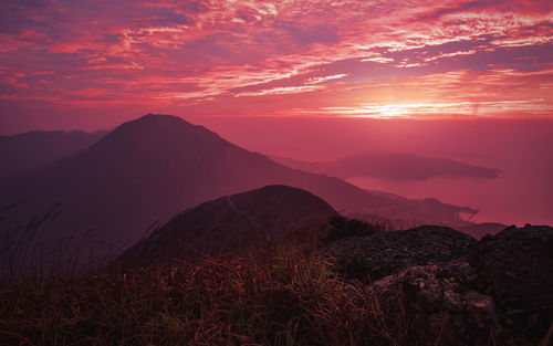 Silhouette mountains against dramatic sky during sunset