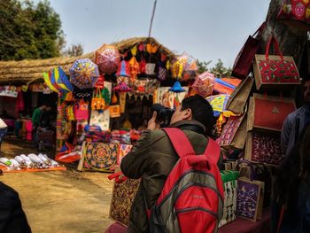 Rear view of man photographing at market stall