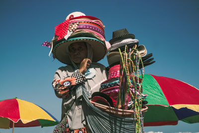 Low angle view of person holding umbrella against clear blue sky