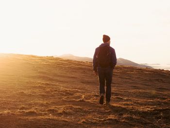 Rear view of man standing on land against sky