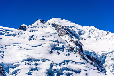 Scenic view of snowcapped mountains against clear blue sky
