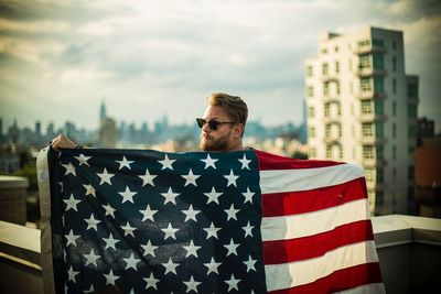 Portrait of man with american flag standing in city