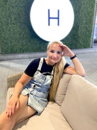 Portrait of a smiling young woman sitting against wall