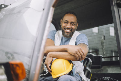 Portrait of smiling mature construction worker with hardhat sitting in vehicle