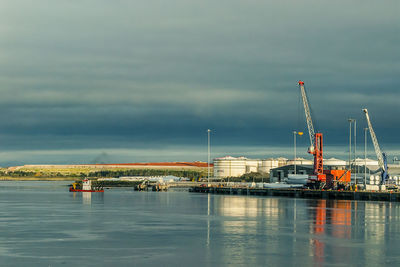 Cranes at harbor against sky