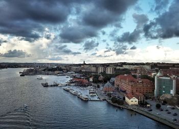 View of river and buildings against cloudy sky