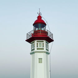 Lighthouse by sea against clear sky