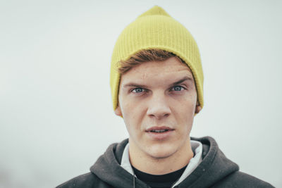 Young man wearing knit hat standing against wall during winter