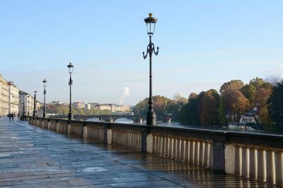 Street lights by bridge in city against sky