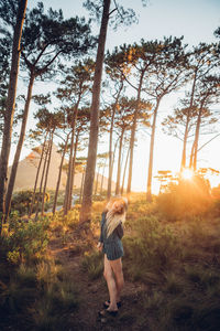 Rear view of young woman standing in forest