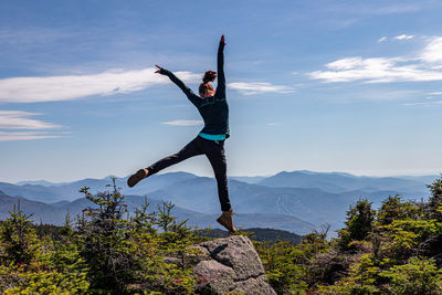 Man with arms raised against mountain range against sky