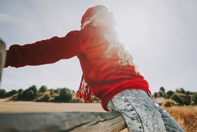 Midsection of woman with red umbrella against sky