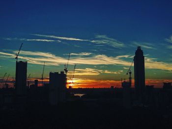 Silhouette of buildings against cloudy sky at sunset