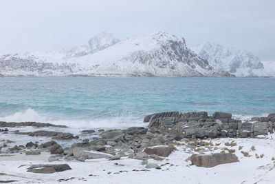 Scenic view of sea and snowcapped mountains against sky