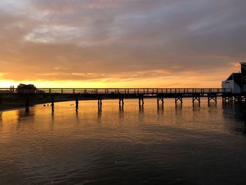 Pier over sea against sky during sunset