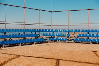 Empty chairs at beach against clear blue sky