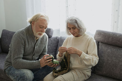 Senior couple sitting on couch knitting