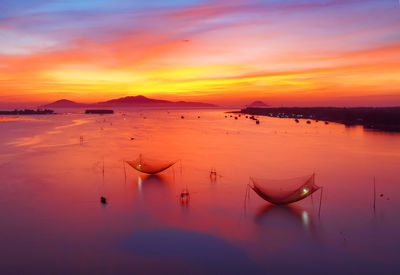 Boats moored in sea against romantic sky at sunset