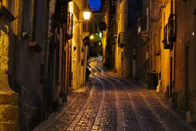 Narrow street amidst buildings at night