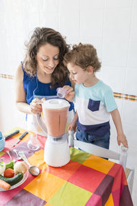 Woman preparing food while standing with son