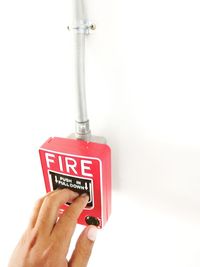 Close-up of hand holding fire hydrant button on wall