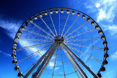 Low angle view of ferris wheel against cloudy sky