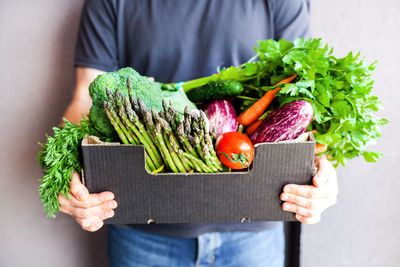 Midsection of man holding vegetables in box