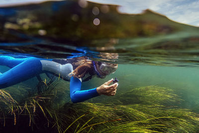 Woman searching sea food while diving in to sea