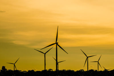 Silhouette windmill on field against sky during sunset