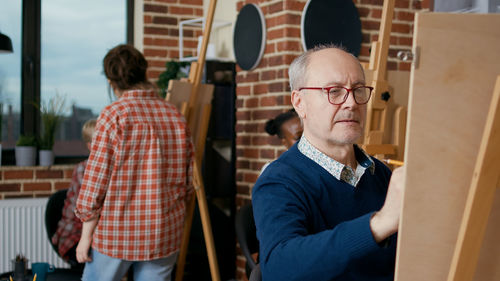 Senior man sketching on canvas at workshop