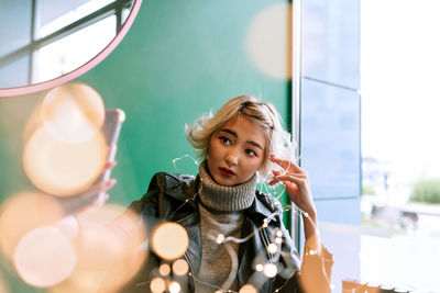 Young woman looking away while holding string lights