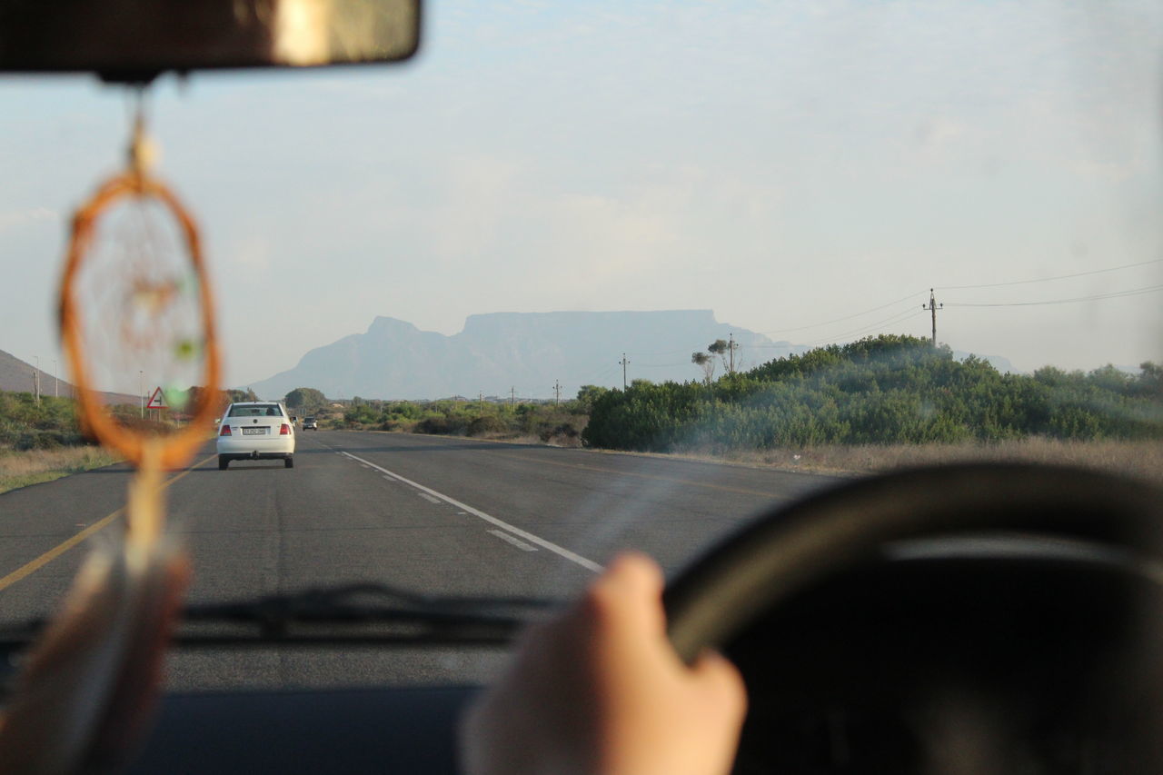 CLOSE-UP OF HAND HOLDING CAR WINDSHIELD