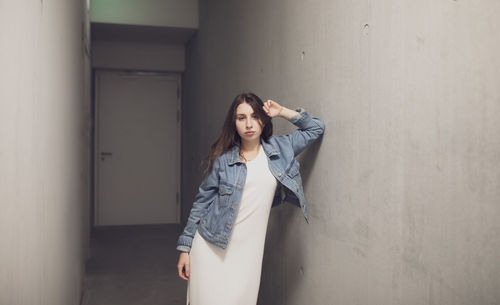 Portrait of young woman leaning on wall