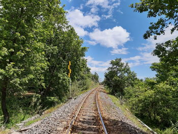 Railroad tracks by trees against sky