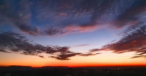 Silhouette landscape against dramatic sky during sunset