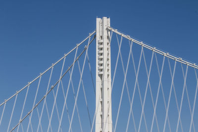 Low angle view of suspension bridge against clear blue sky